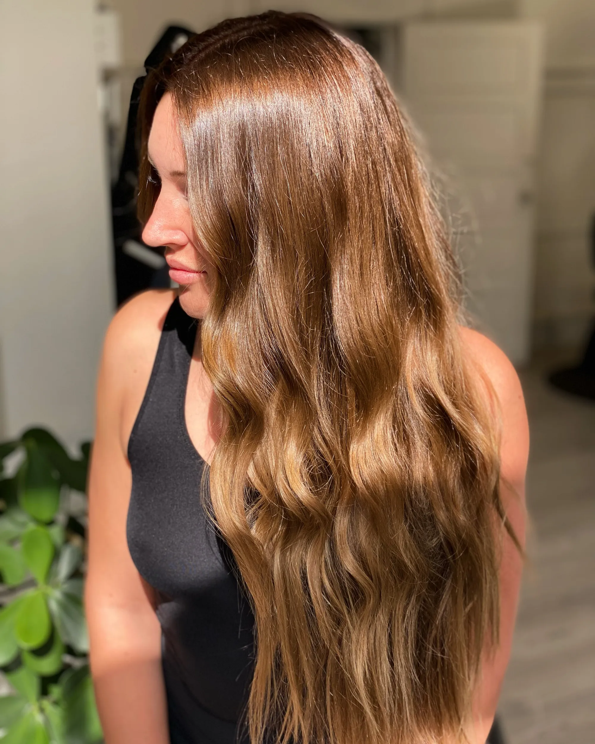 Long golden-brown hair falling in soft waves, sunlit balayage brightening through the mid-lengths and ends.