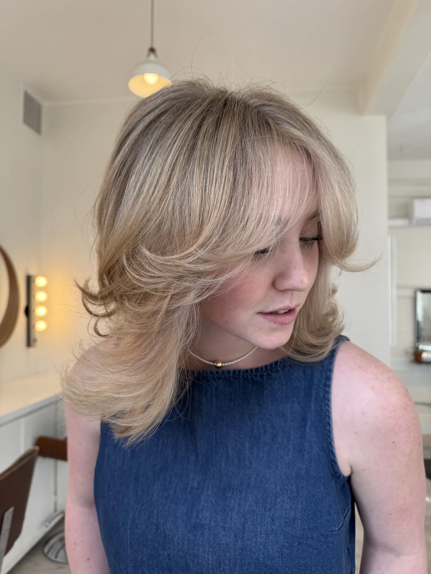 Shoulder-length blonde blown out into a soft rounded shape, with warm creamy tone through the ends.